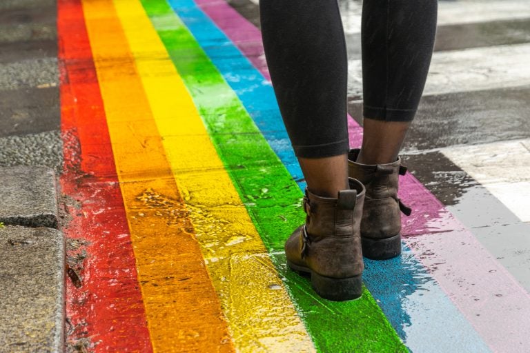 legs walking on lgbtq rainbow crosswalk