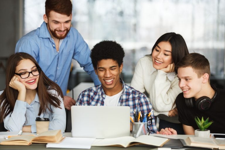 happy students watching tutorial videos on laptop