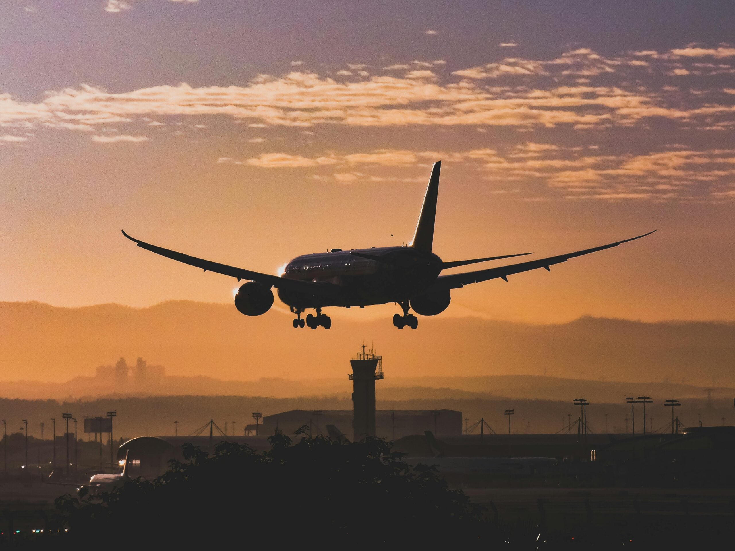 a plane landing in an airport in minimal sunlight